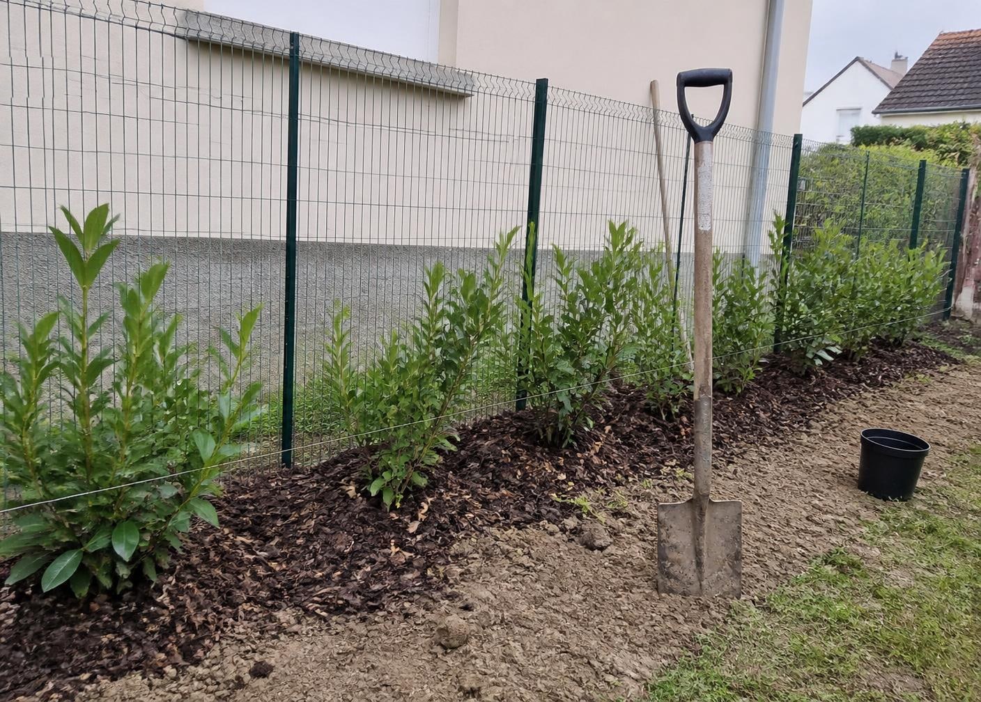 Jardin paysager neuf avec pelouse verte, massifs fleuris et allée en gravier
