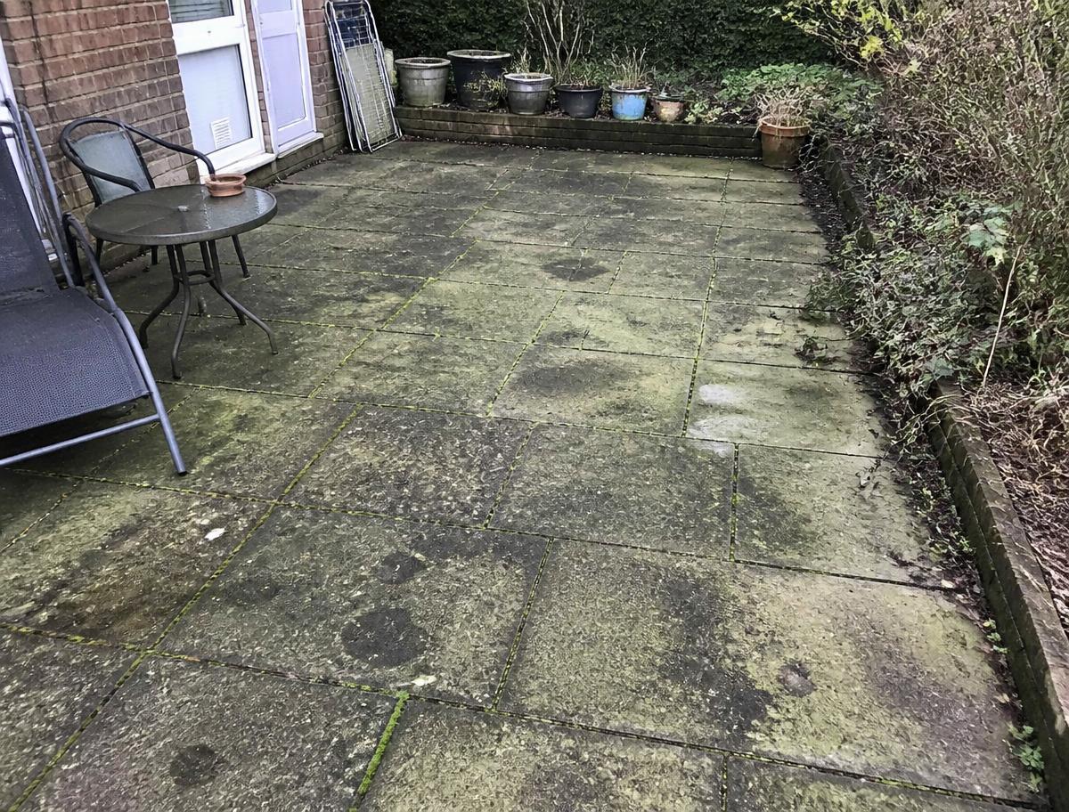 Terrasse en dalles couverte de mousses vertes et de taches noires avant nettoyage